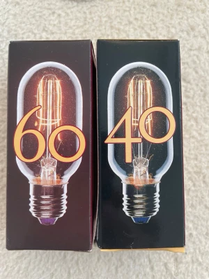 Utomhuslampor & glödlampor Konstsmide - Två klassiska utomhusvägglampor från Konstsmide, modell Gnosi Lyktan, i vit metall med glas och två glödlampor på 40W och 60W. Perfekt för att lysa upp entrén eller trädgården med en stilren och tidlös design.