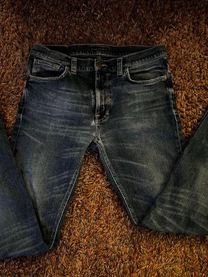 Mörkblå raka jeans från Nudie - Snygga mörkblå jeans från Nudie med raka ben och i storlek W33 L34! På tredje bilden syns färgen bättre 😇 ‼️Den har trasig ficka på vänstra sidan ‼️ Perfekta för en avslappnad och trendig look. 
