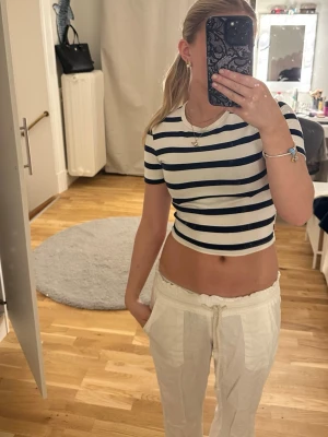 Randig croppad topp i bomull - Snygg croppad topp med marinblå och vita ränder. T-shirten har korta ärmar och rund halsringning. Perfekt för en trendig och avslappnad stil. Materialet känns mjukt och skönt mot huden. För den som vill ha en liten hint av Copenhagen style I sin garderob 