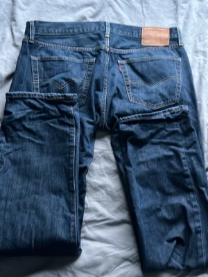 Levi's 501 Blå - Ett par 501 blå jeans från Levi's med raka ben,. Jeansen har tydliga sömmar, läderpatch bak i midjan och den ikoniska röda Levi's-taggen på , perfekta för en avslappnad stil. W34 L32, pris kan diskuteras 