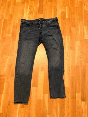 Jeans från Jack&Jones - Snygga mörkblå jeans från Jack&Jones med raka ben och knappgylf. Klassisk femficksmodell i stretchigt denimtyg. Perfekta för en avslappnad och trendig look.