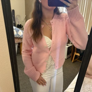 Ljusrosa stickad kofta med knappar - Söt ljusrosa stickad kofta. Koftan har långa ärmar och stängs med matchande knappar framtill. Så söt passar både till vintern och till sommaren💕