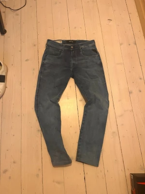Blå slim fit jeans från Replay - Snygga blå jeans från Replay i modellen Anbass med slim fit-passform. Klassisk femficksdesign, normal midja och dragkedjegylf. Perfekta för en trendig och avslappnad look.