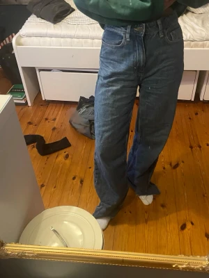 Blåa loose fit jeans med hög midja - Säljer ett par blåa loose fit jeans med hög midja och raka ben. Jeansen har klassiska fem fickor och är gjorda i ett kraftigt denimtyg. Perfekta för en avslappnad och trendig stil.