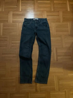 Levi's 511 mörkblå jeans herr - Säljer ett par klassiska Levi's 511 jeans i mörkblå denim. Modellen är slim fit med fem fickor och snygga kontrastsömmar. Ikonisk läderpatch bak i midjan och röd Levi's-tagg på bakfickan. Perfekta för en stilren och avslappnad look.