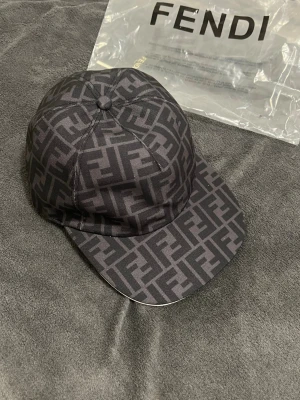 Fendi Keps  - Säljer en svart keps från Fendi med det klassiska FF-monogrammet i grått över hela kepsen.  Säljer pågrund av ej behov av den är perfekt och bra pris 600kr 