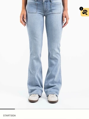 Ljusblå bootcut jeans med fickor - Säljer ett par ljusblå bootcut jeans med stora framfickor och klassiska bakfickor. Jeansen har hög midja och är tillverkade i mjuk denim med lätt stretch. Storlek EU36 TALL 