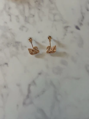 Guldiga örhängen i form av svanar - Snygga örhängen i guldton med glittriga svanar. En klassisker som även matchar halsbandet i min andra annons. Väldigt fint skick och helt oanvända. Original pris 1000 därav priset. Perfekt för dig som vill va lite extra!