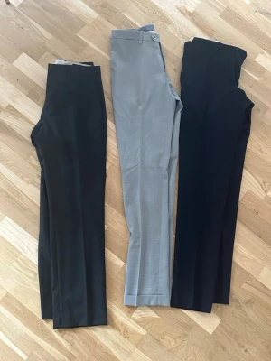 Kostymbyxor i svart, grått och marinblått - Välj färg eller köp tre stycken / Säljer tre par klassiska kostymbyxor i svart, ljusgrått och marinblått. Byxorna har raka ben, pressveck och hällor för bälte. Perfekta för en stilren look. Materialet är troligtvis en blandning av polyester och viskos för en mjuk känsla.