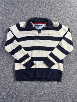 Tommy Hilfiger halfzip stickad tröja L 16-18 (S/M) - Stickad halfzip från Tommy Hilfiger i storlek L (16–18), motsvarar ungefär S/M. Marinblå och vitrandig i klassisk preppy stil med broderad logga framtill.  📏 Märkt L (16–18) – passar S/M 📐 Mått visas i bilderna ✨ Skick: Fint skick – skicket visas i bilderna  Perfekt till vardag, skola eller lager-på-lager.  💸 Följ mig så får du 10% rabatt på köpet!