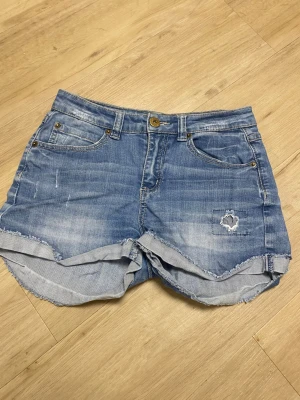Jeansshorts labindustries strl 170 - Jeansshorts med fem fickor och dragkedja framtill. Shortsen har en sliten look med fransiga benslut och broderade detaljer på bakfickorna.