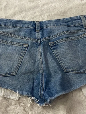 Blå slitna jeansshorts med fransar - Snygga jeansshorts. Använt fåtal gånger. Säljer då de inte kommer till användning💗