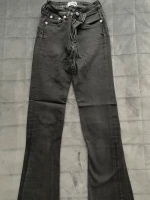 Svarta bootcut jeans - Säljer ett par svarta bootcut jeans. Jeansen har bälteshällor, knappgylf och är tillverkade i stretchigt denimtyg. Jeansen är toppen för dig som letar efter en trendig look att ha i skola, jobb eller var som helst. Passar med stickat, hoodies, koftor, linnen, toppar och blusar. 