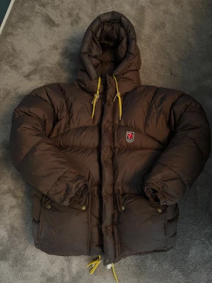 Fjällräven jacka  - Fjällräven vinterjacka i storlek XXS. Köpt på Plick men inte använt så mycket. Små skavanker. Lite ”fett” fläckar tror jag som man ser på luvan tex. Går att få bort i kemtvätt. 