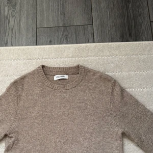 Stickad Tröja Från Strömberg - Säljer en stilren beige tröja från Strömberg. Den är i ett mjukt och bekvämt material, perfekt för både höst och vår. Den italienska flaggan på kanten ger en snygg detalj. Den sitter som s/xs