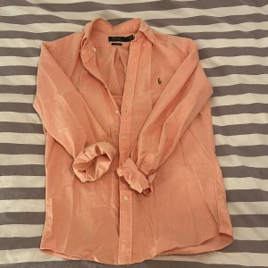 Persikofärgad skjorta från Polo Ralph Lauren - Riktigt snygg skjorta från Ralph Lauren. Har använt den 3-4 gånger så förvänta dig en skjorta som är precis som nyköpt. 10/10 skick med det sagt😎 Skjortan köptes för 1800kr på Åhléns (kvitto finns!). Hör av er vid frågor eller funderingar! 