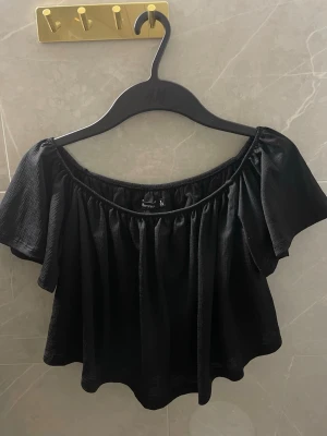 Svart offshoulder topp från Bershka - Trendig svart offshoulder topp från Bershka med korta, vida ärmar och luftig passform. 