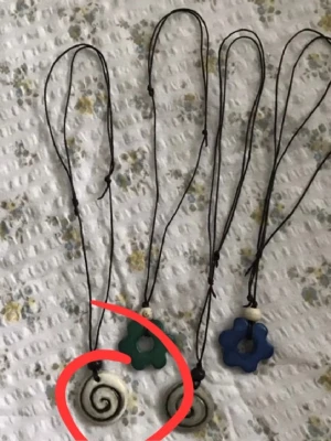 Halsband med spiralformad berlock - Säljer ett handgjort halsband med svart snöre och en vit spiralformad berlock i keramik eller lera