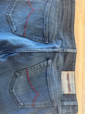 Blå jeans från Jacob Cohen - Snygga blå jeans från Jacob Cohen med raka ben och klassisk femficksmodell. Bakfickorna har röd dekorationssöm och jeansen har en patch med logga i midjan.  Modell 688 som är en av dem populäraste modellerna har även japansk denim som är mycket populärt