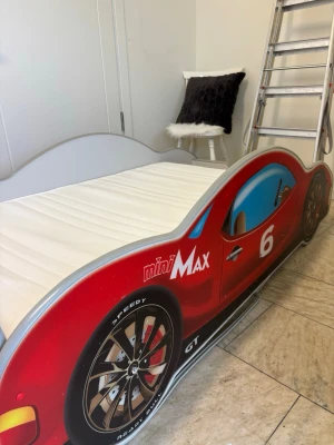 Bilformad barnsäng miniMax - Säljer en cool barnsäng i form av en röd sportbil med texten miniMax och siffran 6 på sidan. Sängen har detaljerade hjul, blå fönster och svarta lister. Perfekt för dig som gillar bilar och vill ha ett unikt inslag i barnrummet.