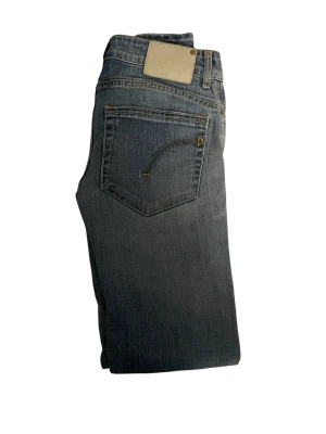 Dondup jeans - Snygga blå bootcut jeans från dondup med klassisk femficksdesign och ljusa slitningar framtill. Jeansen har en beige patch bak i midjan och kontrastsömmar. Tillverkade i mjukt denimtyg som ger en bekväm passform.