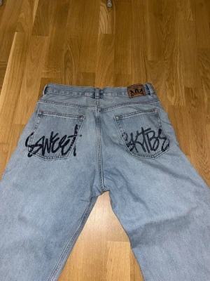 Ljusblå baggy jeans från SWEET SKTBS - Baggy ljusblå jeans från SWEET SKTBS med graffiti-inspirerad text på bakfickorna. Klassisk femficksmodell i denim med raka ben och hög midja. Pris går att diskutera 💞