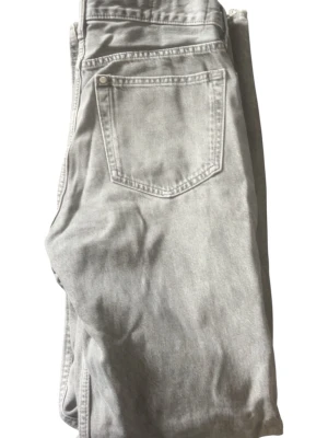 Gråa raka jeans i tvättad look - Snygga grå jeans med rak passform och klassisk femficksdesign. Jeansen har en tvättad finish som ger en cool och avslappnad vibe. Perfekta att matcha med sneakers och hoodie för en trendig stil.