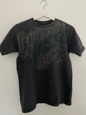 Svart t-shirt från Hurley - Cool svart t-shirt från Hurley med stort grafiskt tryck över bröstet. Klassisk rund halsringning och korta ärmar. Perfekt för dig som gillar streetwear och vill ha en unik look. Den stora grafiken och den ”washed” looken ger en skate-estetik. Köpt under tidigt 2000-tal. 