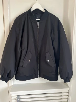 Oversized bomberjacka från Mango - Snygg svart bomberjacka från Mango med oversized passform, silverfärgad dragkedja och två fickor med lock och tryckknappar. Jackan har ribbade muddar vid ärmslut och nederkant samt klassisk rund krage. Perfekt för våren! Stl S men passar en Medium användare.