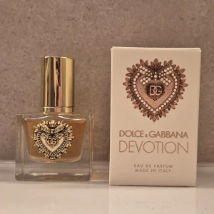 Dolce & Gabbana Devotion EdP - Lyxig parfym från Dolce & Gabbana, Devotion Eau de Parfum. Flaskan är fyrkantig i genomskinligt glas med guldfärgat lock och ett detaljerat hjärta i guld på framsidan. Doften är elegant och flaskan har exklusiv design med vackra detaljer.