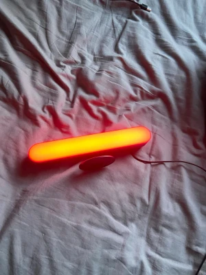 LED-ljusrör med röd belysning - Säljer ett avlångt LED-ljusrör med stark röd belysning. Lampan har en rund fot och ansluts med USB-kabel. Perfekt som dekoration eller stämningsbelysning i rummet. Modern design i plast och enkel att placera tack vare den smidiga formen.