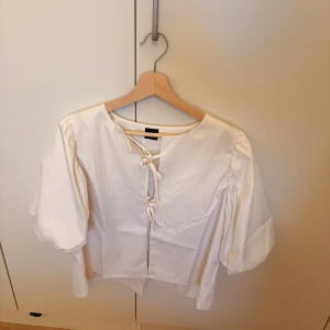 Vit blus med knytning från Gina Tricot - Säljer denna blus från Gina Tricot, helt oanvänd i storlek L