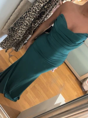 Grön axelbandslös långklänning  - Snygg smaragdgrön axelbandslös balklänning eller för andra tillfällen. Är i storlek Xs men passar även dig i strl S. Materialet är stretchigt och inte tajt och den har som en korsett inuti vid magen. Verkligen jätte fin klänning som jag hade under min bal och den har användts 1 gång. Och jag är 159 centimeter, jag skulle säga att den var ganska lång på mig.