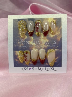 CrimsonGold (S);Medium Almond - Unika handgjorda press-on naglar i storlek S: 15 mm, 11,5 mm, 12 mm, 11 mm, 9 mm . Designen har nude bas, vinröda cateye french tippar och detaljer i guld. Några naglar har röda handmålade blommor och alla har 3D-gulddetaljer som ger en lyxig känsla. Perfekt för dig som vill sticka ut med konstnärliga naglar.