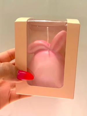 Rosa kaninformat ljus i presentförpackning - Söt rosa ljus formad som en kanin med öron, levereras i en ljusrosa presentförpackning med genomskinligt fönster. Perfekt som dekoration eller present. Ljusets material är vax.