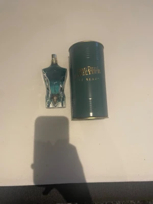 Jean Paul Gaultier Le Beau parfym - Unik parfym från Jean Paul Gaultier, Le Beau, med en flaska formad som en manlig torso i blått glas och gulddetaljer. Kommer i en elegant metallburk med guldfärgad text. Perfekt för dig som vill sticka ut med en ikonisk doft.  Ca 67 ml kvar.