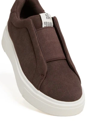 Bruna sneakers  - Snygga sneakers med minimalistisk design och vit tjock sula. Skorna är tillverkade i textilmaterial och har en unik överdel utan klassiska snörningar, vilket ger ett clean och modernt uttryck. Knappt använda.