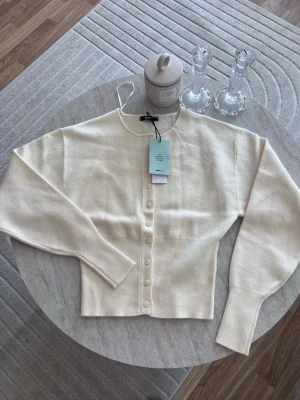 shaped knitted cardigan - Snygg krämvit kofta från Gina Tricot med rund halsringning och knappar framtill. Tillverkad i 50% Lenzing Ecovero viskos, vilket gör den mjuk och skön. Kortare modell med ribbade muddar och stilren look som passar till allt. Nypris 399kr!