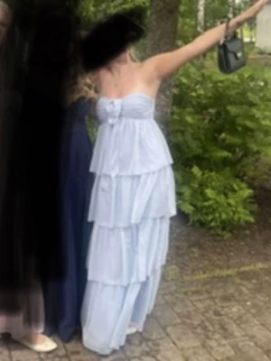 Ljusblå axelbandslös volangklänning - Säljer min balklänning som endast är använd en gång. Klänningen har flera lager volanger och axelbandslös design. Klänningen har en söt rosettdetalj framtill och är perfekt för somriga tillfällen. Tillverkad i ett lätt och luftigt material som ger en romantisk känsla.