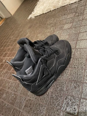 Jordan 4 black cat - Säljer ett par blackcats(helsvarta) Air Jordan 4 sneakers med klassisk siluett, meshpaneler på sidorna och detaljer i mocka. Skorna har svarta skosnören, ikonisk Jumpman-logga på plösen och en sula som ger grym streetstil.