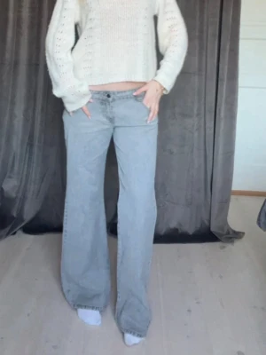 Gråa vida jeans med låg midja - Säljer ett par gråa jeans med låg midja och riktigt breda ben. Jeansen har klassisk femficksdesign och stängs med knapp och dragkedja. Perfekta för dig som gillar en avslappnad och trendig look. Materialet är mjukt denim i bomull. Helt oandvända och nya