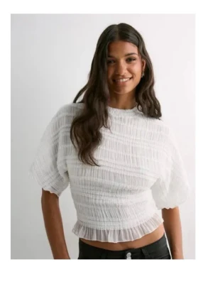 Vit volangblus med kort ärm - Säljer en söt vit blus med korta ärmar och volangkant nedtill. Toppen har en strukturerad, lätt rynkad yta och är heeelt oanvänd💕