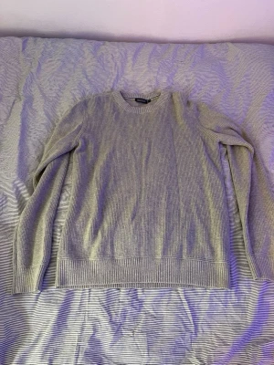 Ljusgrå stickad tröja Race Marine - Snygg ljusgrå stickad tröja från Race Marine med rund halsringning och ribbade muddar vid ärmslut och nederkant. Tröjan har en klassisk rak passform och är perfekt för lager på lager. Materialet känns mjukt och bekvämt.