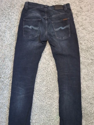 Mörkblå slim fit jeans från Nudie - Snygga mörkblå slim fit jeans från Nudie med klassiska fem fickor. Jeansen är modellen thin finn och är storlek w32 l34.