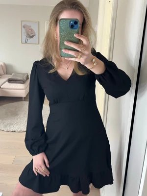 Svart kort klänning med volang - Fin svart klänning från primark! Klänningen har v-ringning, långa puffärmar och volang. Klänningen är figursydd i midjan och är tillverkad i ett lätt, tyg som ger en fin figur. Perfekt för dig som gillar stilrena och trendiga plagg.🖤🖤Helt ny, använt 1 gång!