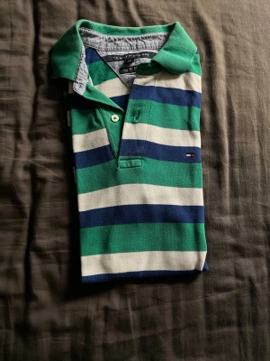 Randig pikétröja från Tommy Hilfiger - Snygg randig pikétröja från Tommy Hilfiger i grönt, vitt och blått i storlek M