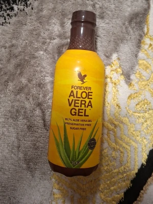 Forever Aloe Vera Gel 1L flaska - Säljer en 1 liters flaska Forever Aloe Vera Gel. Flaskan är gul med brun kork och har tydlig aloe vera-växt på etiketten. Innehåller 99,7% aloe vera, är fri från konserveringsmedel och socker. Perfekt för dig som vill ha ett naturligt tillskott.