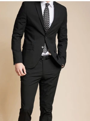 Svart kostym med kavaj och byxor - Stilren svart kostym med klassisk kavaj och matchande byxor. Kavajen har två knappar, fickor med lock och smal passform. Perfekt till skjorta och slips för en dressad look. Strl 42 på kavajen, 29-30 på byxorna. 