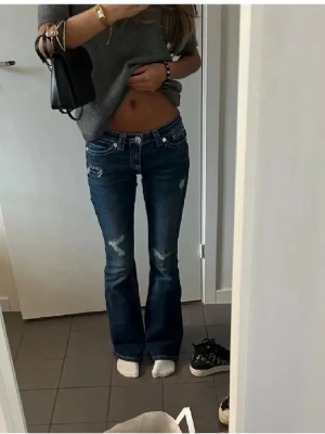 Mörkblå bootcut jeans med slitningar - Snygga mörkblå bootcut jeans med slitna detaljer och låg midja. 