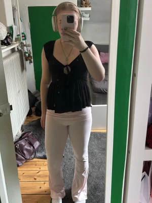 Svart v-ringad linnetopp med knyt - Säljer en svart linnetopp med v-ringning och knyt framtill. Toppen har breda axelband och en luftig, lätt utställd passform som ger en avslappnad look. Perfekt för varma dagar och enkel att styla med olika accessoarer. Aldrig använd 